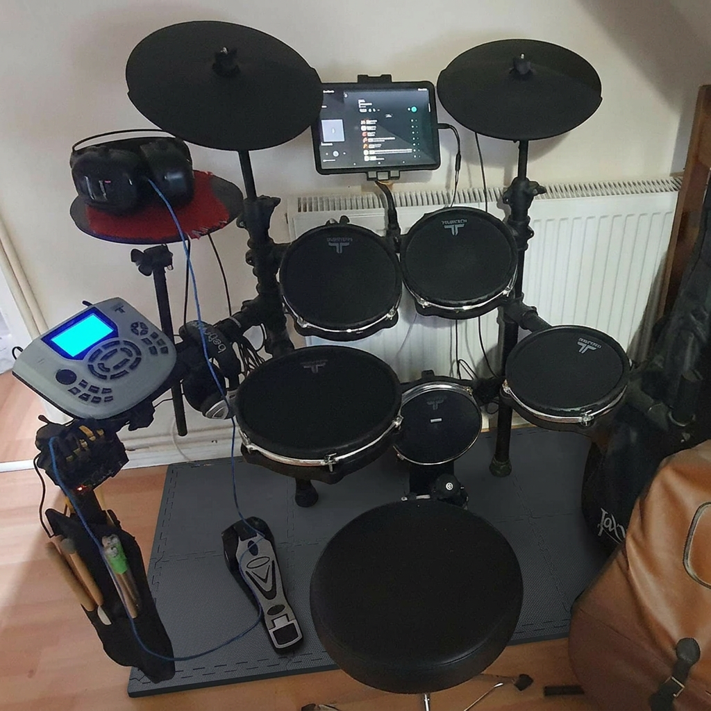 Black extra-thick 2cm interlocking gym mats used under an electronic drum kit to reduce floor noise