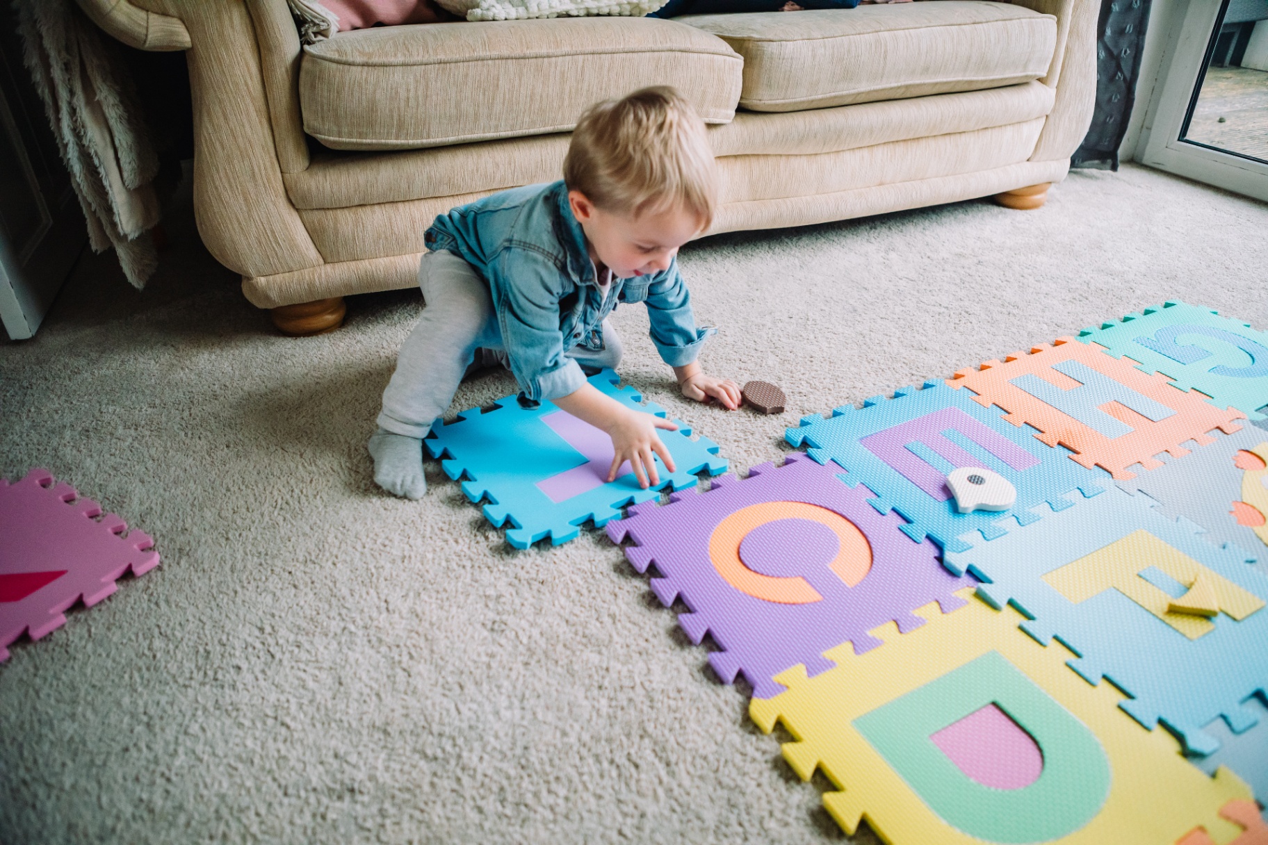 Child playing on the foam puzzle mat in a living room