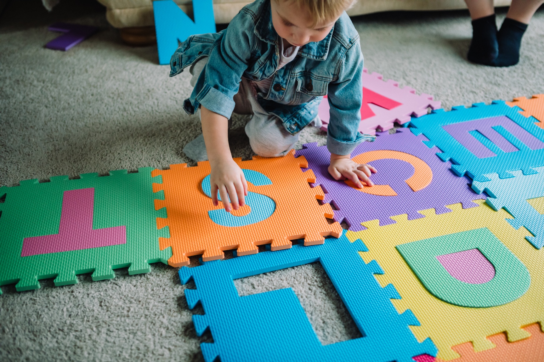 Child assembling the colourful alphabet foam puzzle mat