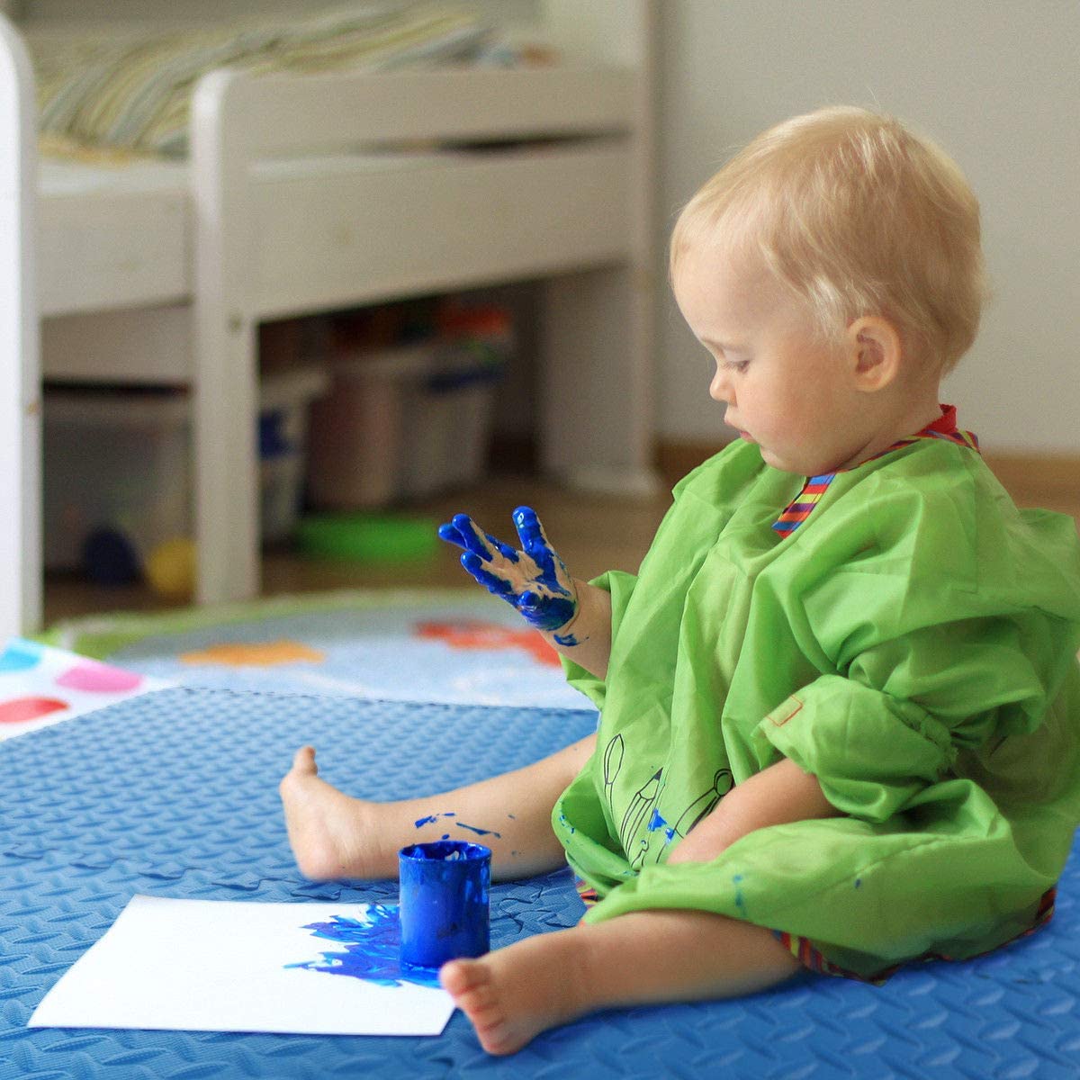 A toddler finger painting on a soft blue ComFy interlocking foam play mat